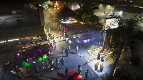 a crowd and lowrider cars at a neon lit night street party in Vice City in an official GTA 6 screenshot