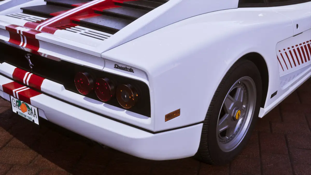 the rear of a white sports car with red stripes and three round tail lights in a Rockstar Games image for GTA 6